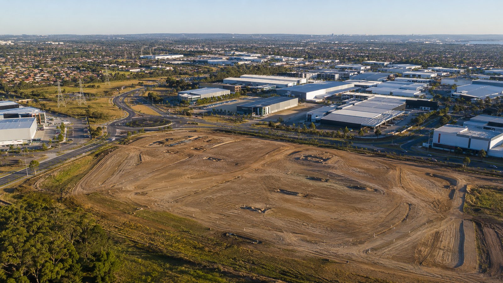 Aerial view of a cleared greenfield development site beside an established industrial precinct